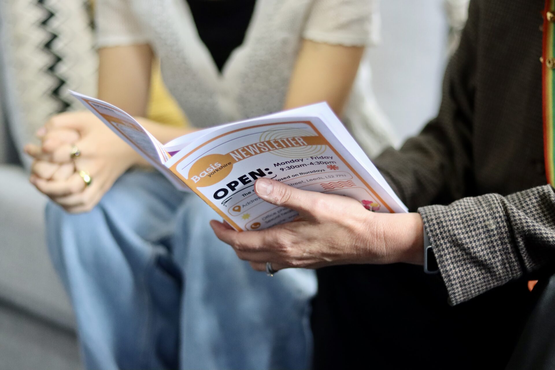 Close up of 2 people's hands looking at a Basis Yorkshire booklet.